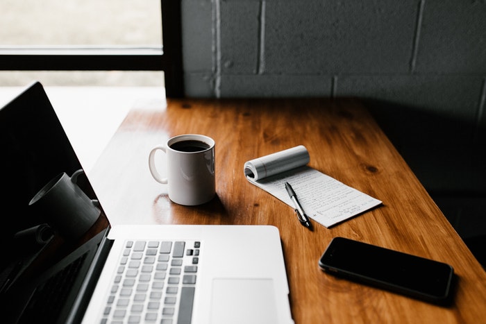 Computer with notebook, with a cup of coffee on the side and mobile phone